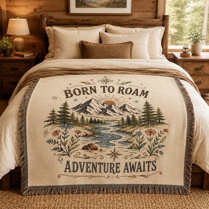 Born to Roam Adventure Awaits woven blanket displayed across a rustic cabin bed