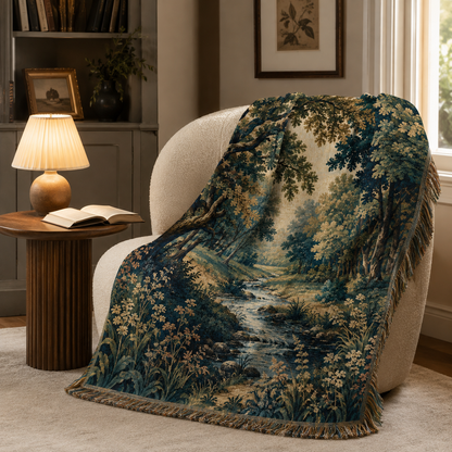 Enchanted forest stream woven blanket displayed on a cozy reading chair beside a lamp and book