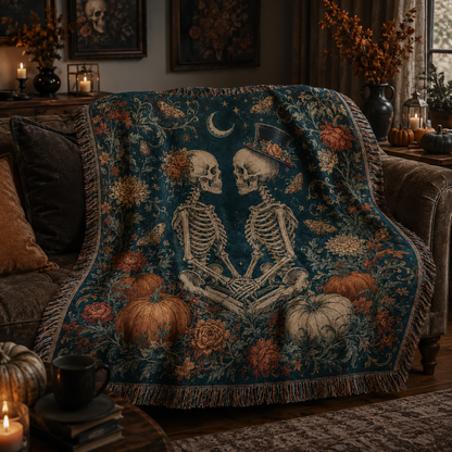 Gothic skeleton couple woven blanket styled on a dark sofa with candles and Halloween pumpkins