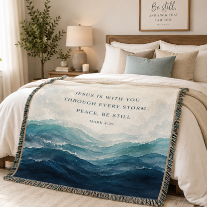 Jesus Is With You Christian woven blanket styled on a cozy bedroom bed with blue ocean waves