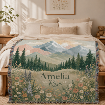 Personalized woven blanket with pastel mountains and wildflowers styled across a bed