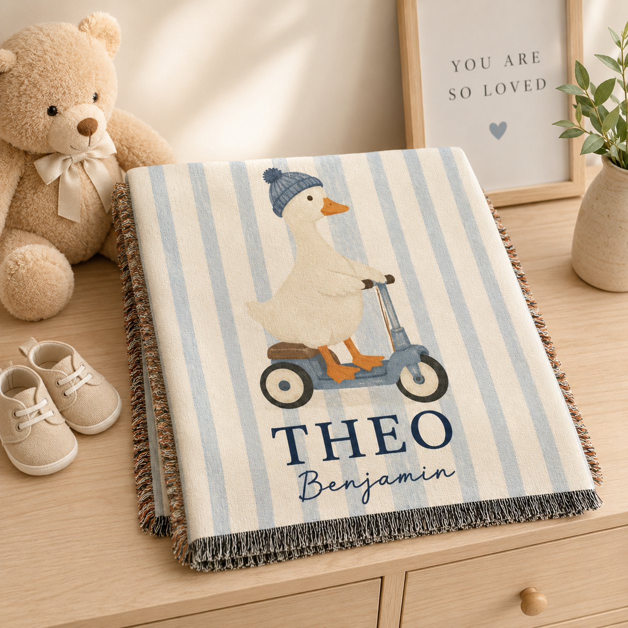 Folded personalized duck scooter baby woven blanket with custom name on nursery dresser