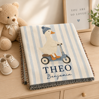 Folded personalized duck scooter baby woven blanket with custom name on nursery dresser