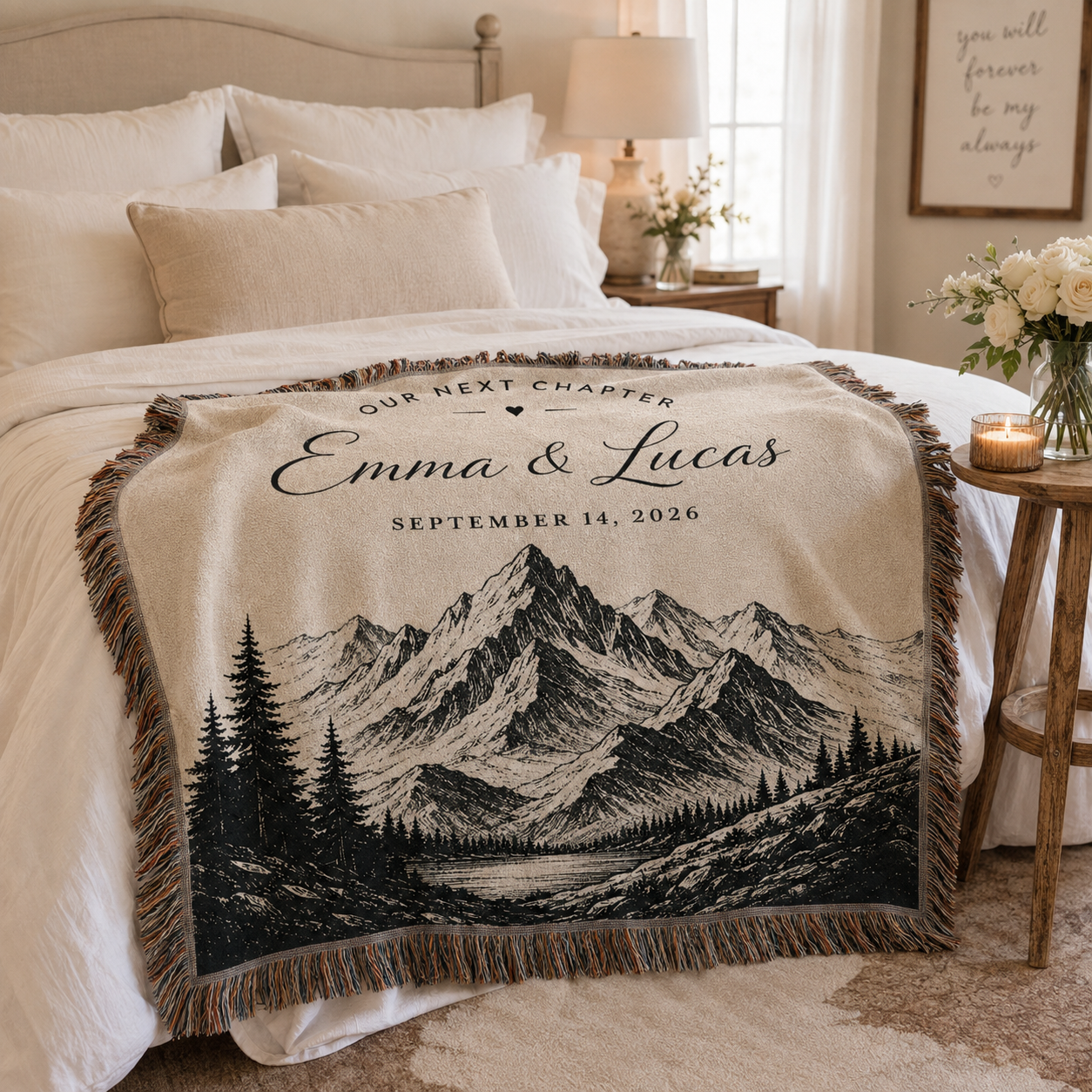 Personalized mountain wedding woven blanket styled across the foot of a romantic neutral bedroom bed
